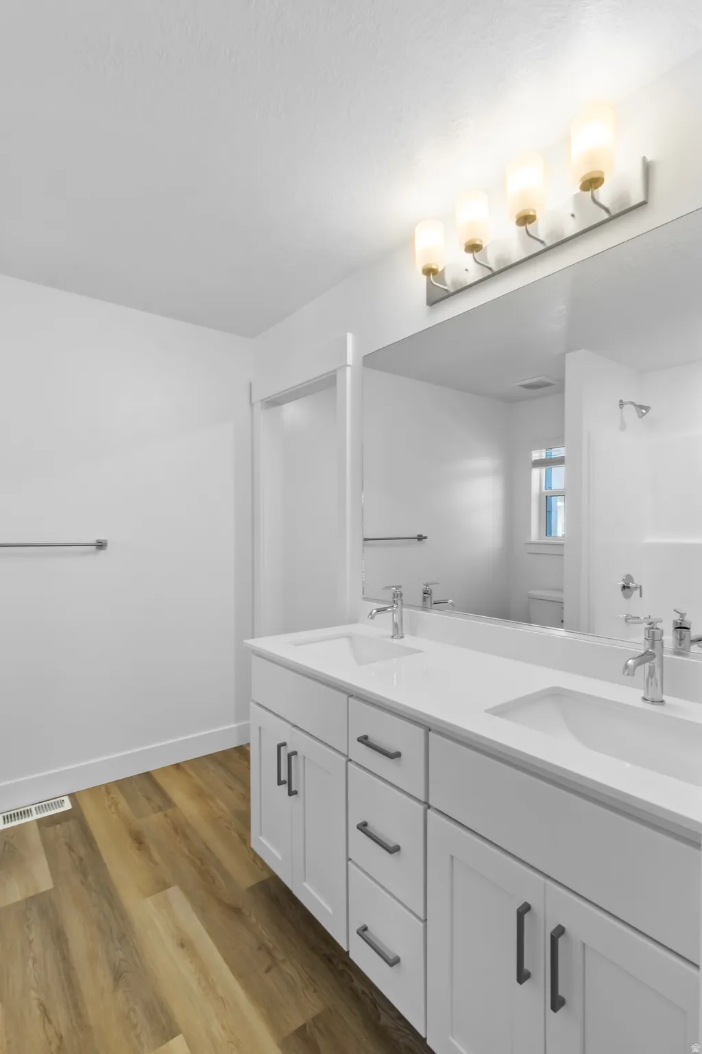 Double vanity featuring white cabinetry with dark pulls, integrated sinks, and chrome faucets