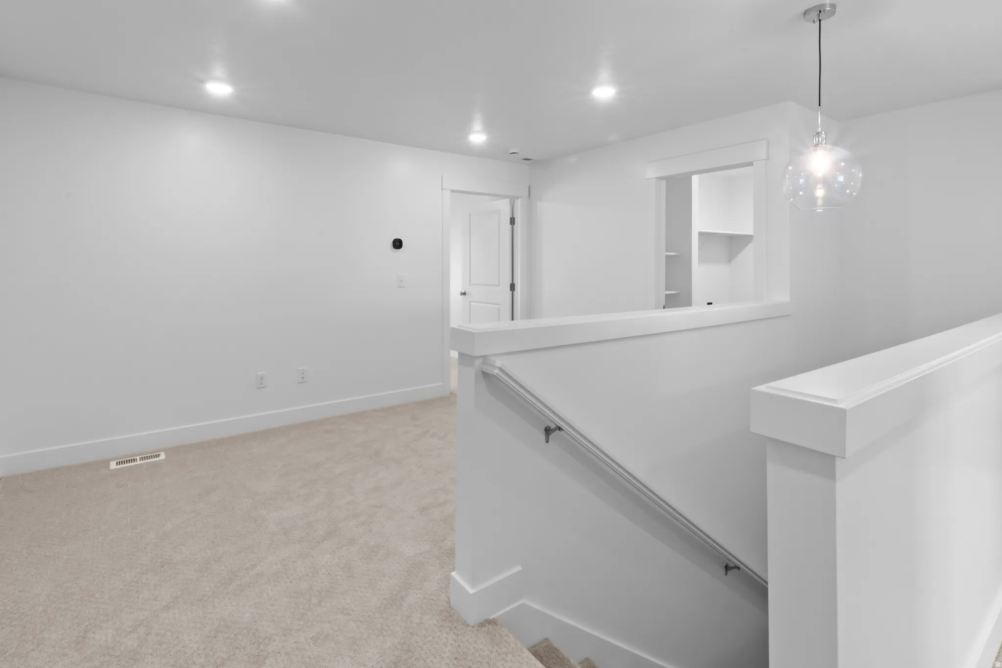 Bright upper-level landing featuring plush carpeting, recessed lighting, and a contemporary glass orb pendant light