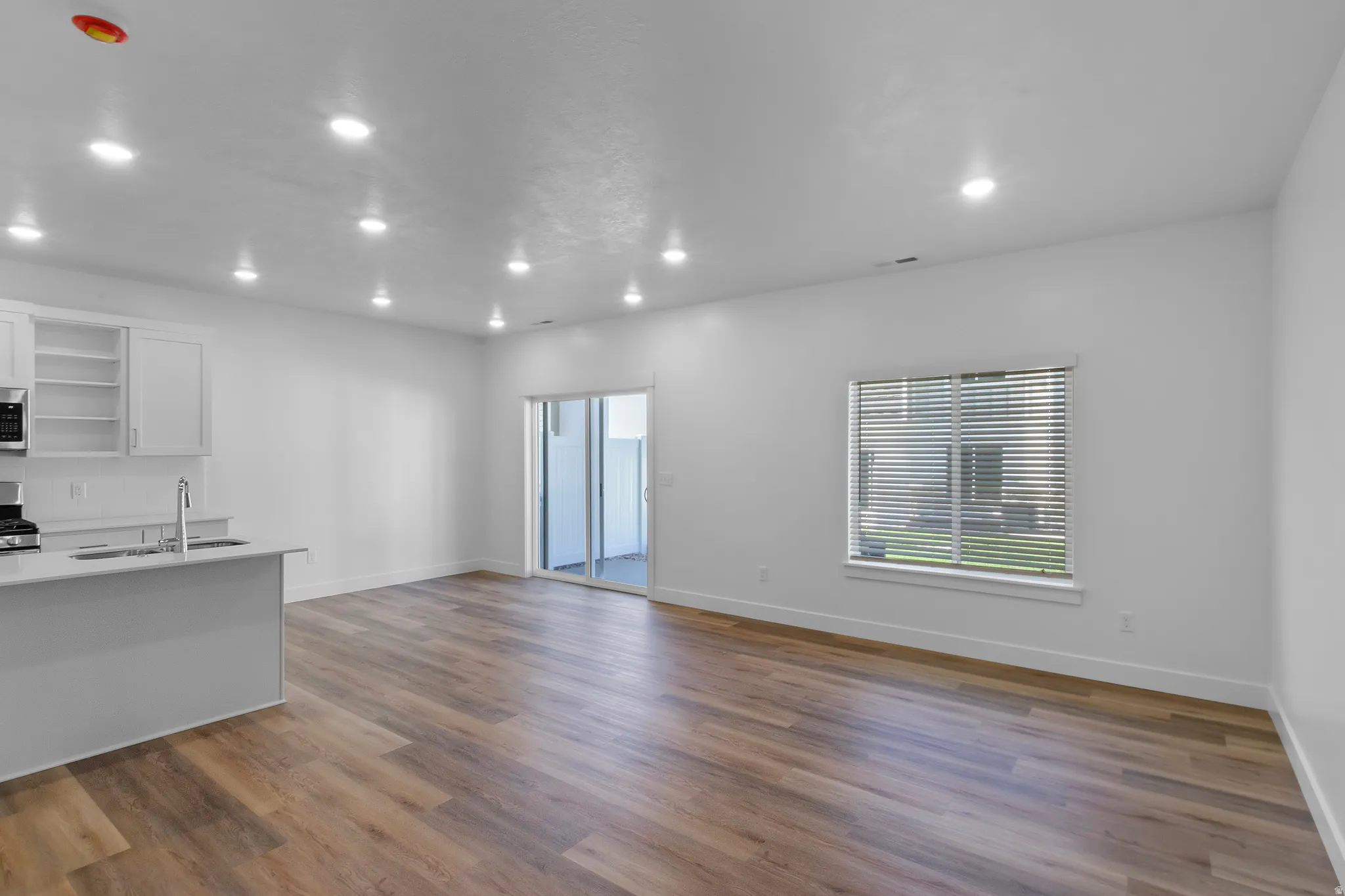 Open-concept living area with wood-finish flooring, recessed lighting, and a sliding glass door to the exterior