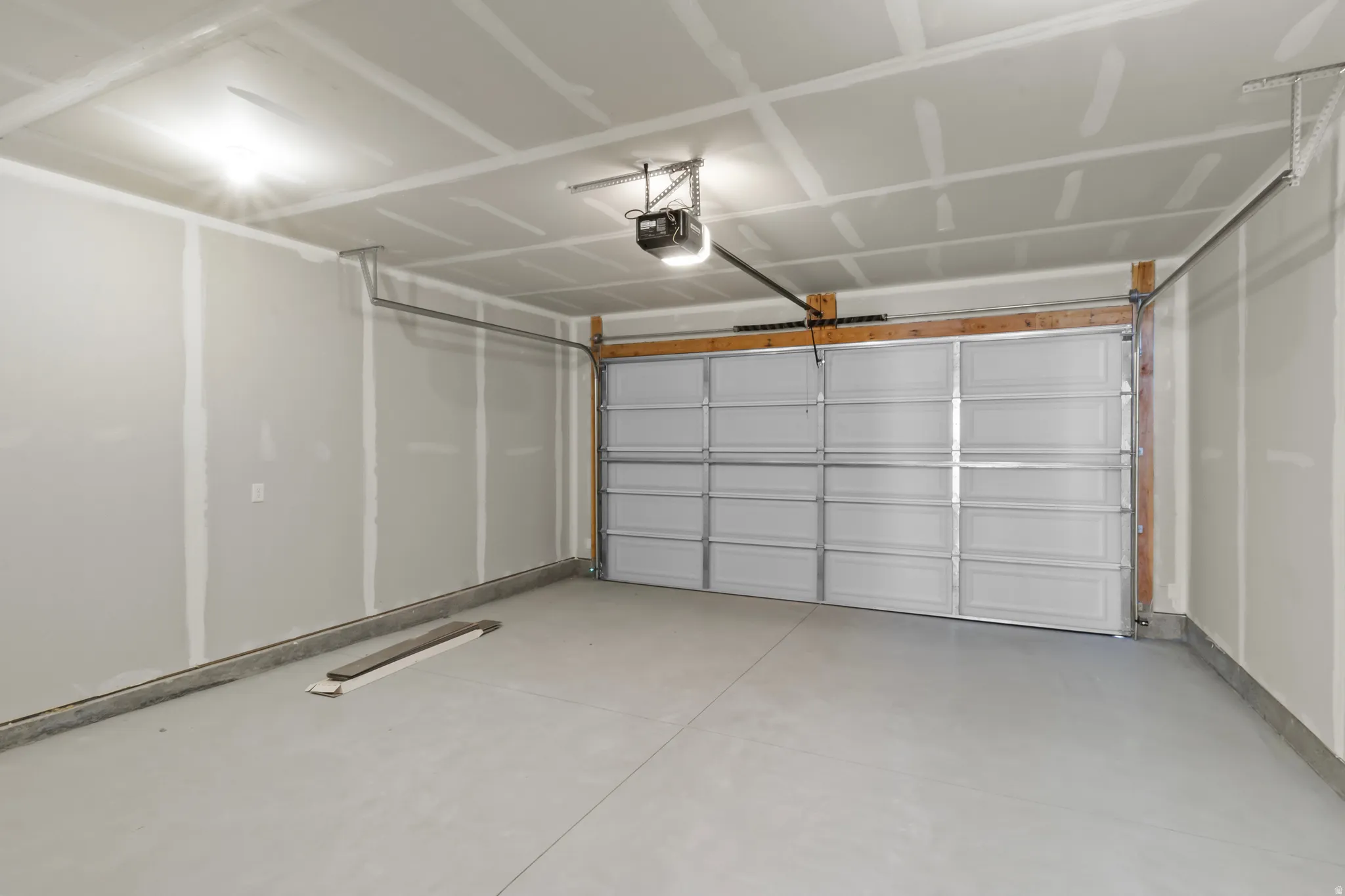 Spacious garage featuring a light gray concrete floor, an overhead garage door opener, and integrated ceiling lighting