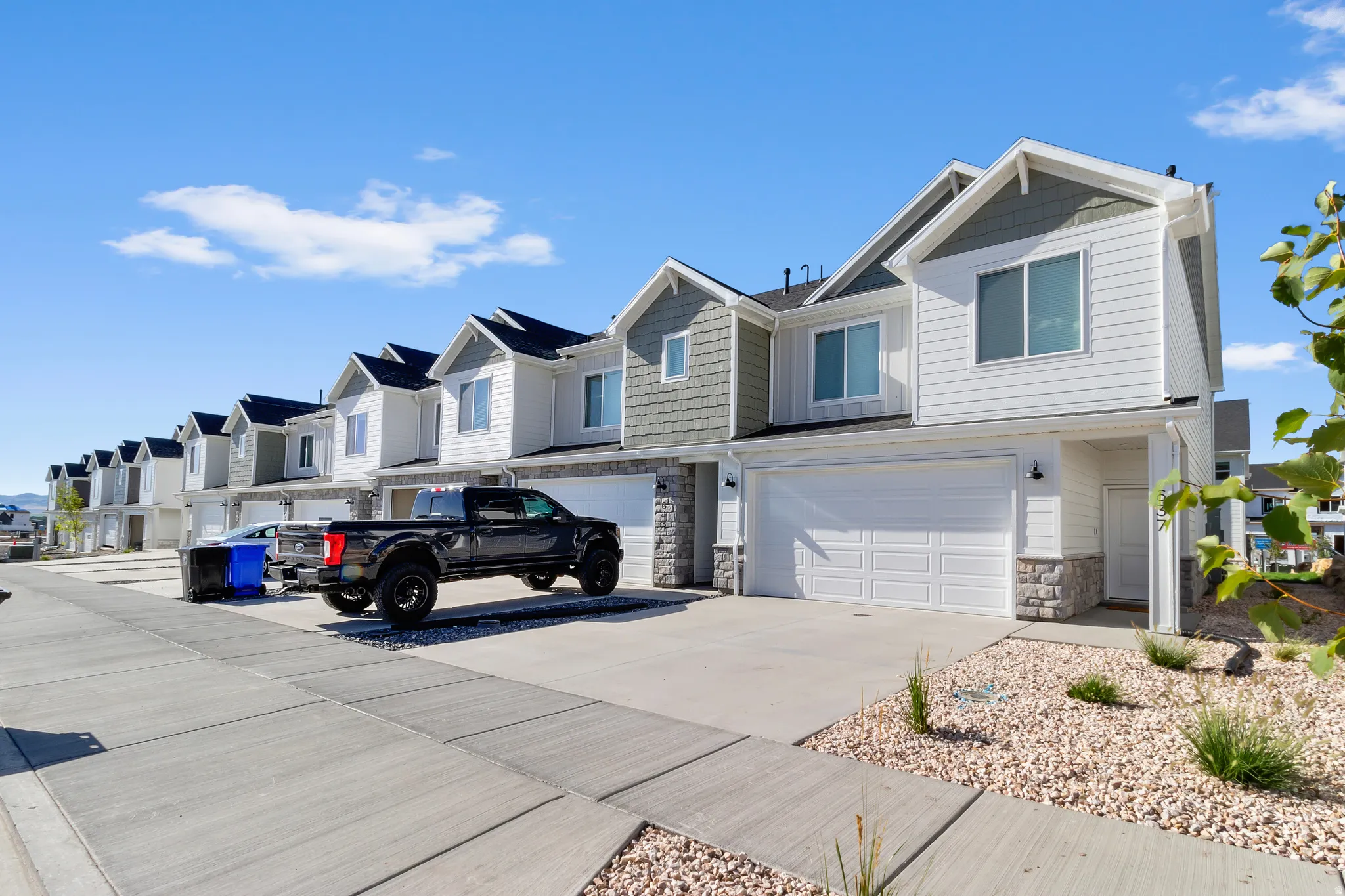 Contemporary townhome exterior featuring a white siding facade, gray shake accents, and stone veneer detailing