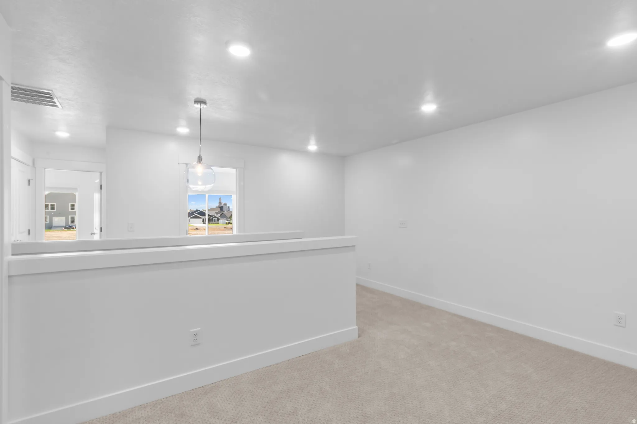 Open concept room with neutral carpeting and bright white walls