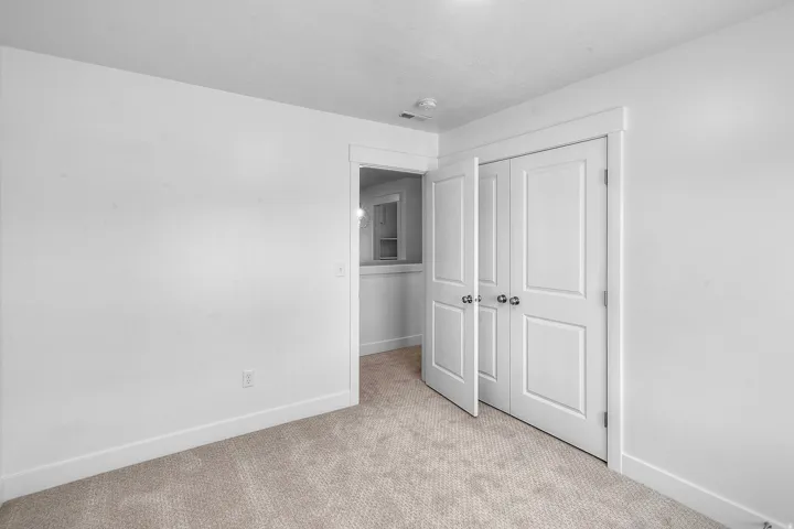 Neutral toned carpeted room featuring a white paneled bi-fold door closet with chrome hardware