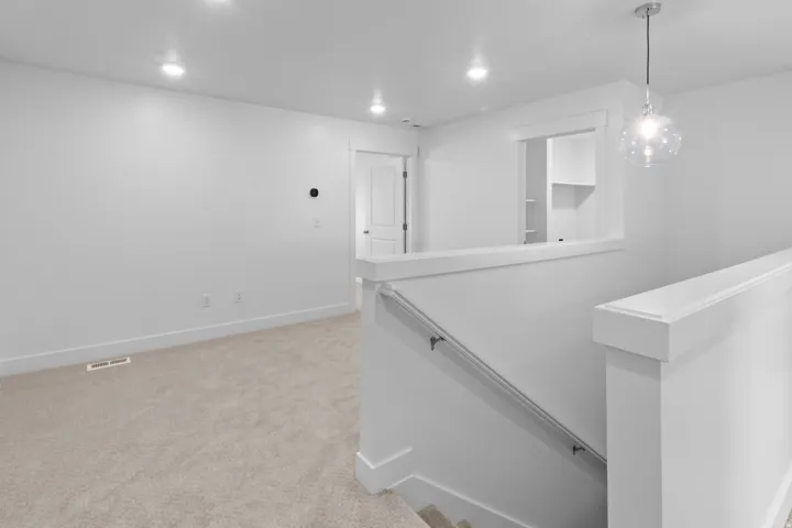 Bright upper-level landing featuring plush carpeting, recessed lighting, and a contemporary glass orb pendant light