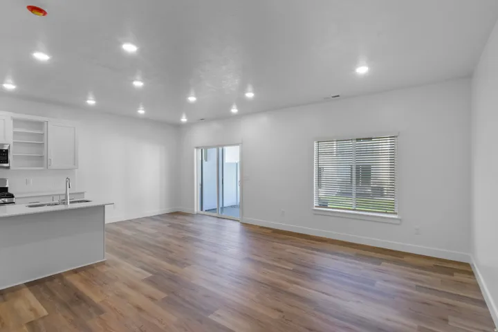 Open-concept living area with wood-finish flooring, recessed lighting, and a sliding glass door to the exterior