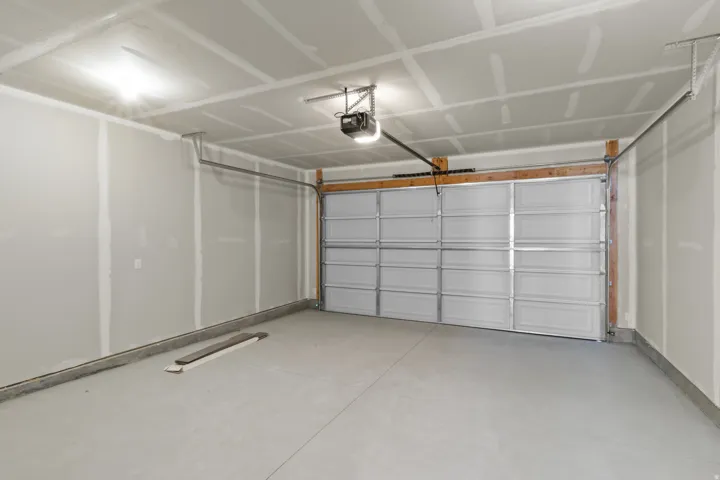 Spacious garage featuring a light gray concrete floor, an overhead garage door opener, and integrated ceiling lighting