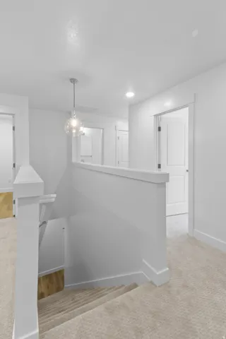Carpeted staircase with white balustrade and contemporary pendant light fixture