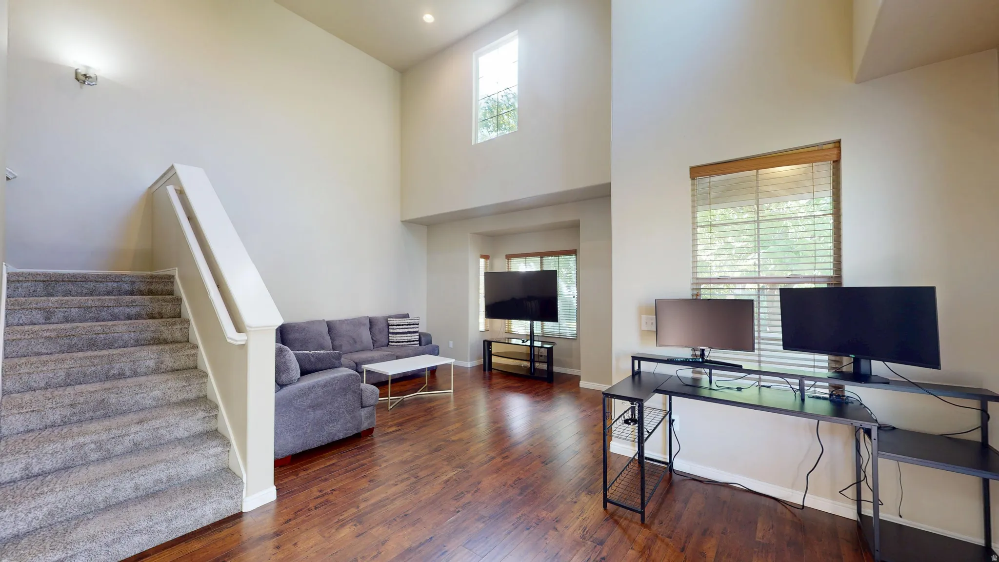 Living area featuring wood-finish flooring and a carpeted staircase with white balusters