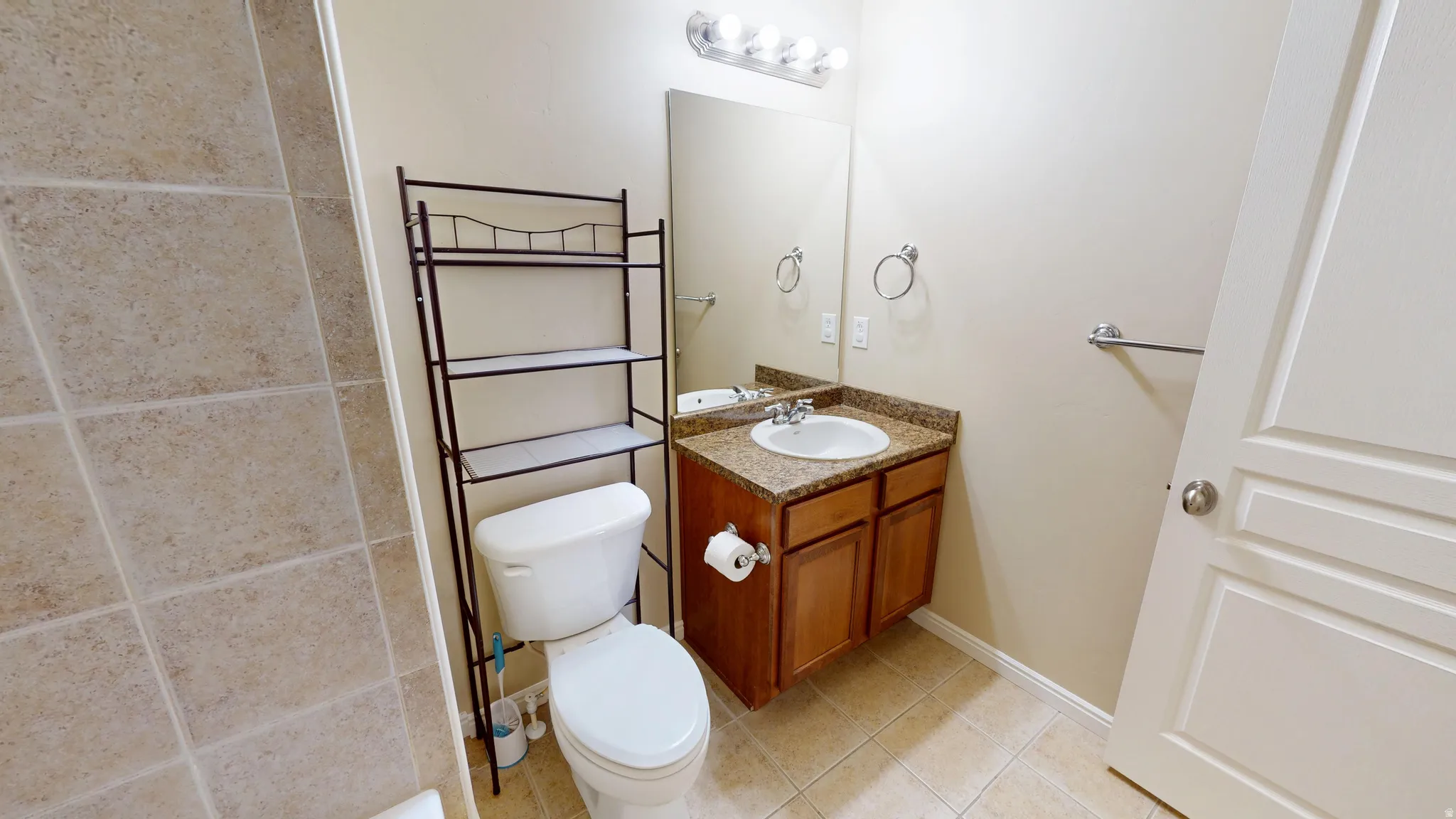 Bathroom featuring a vanity with a surface-mount sink, integrated mirror, and a granite-patterned countertop