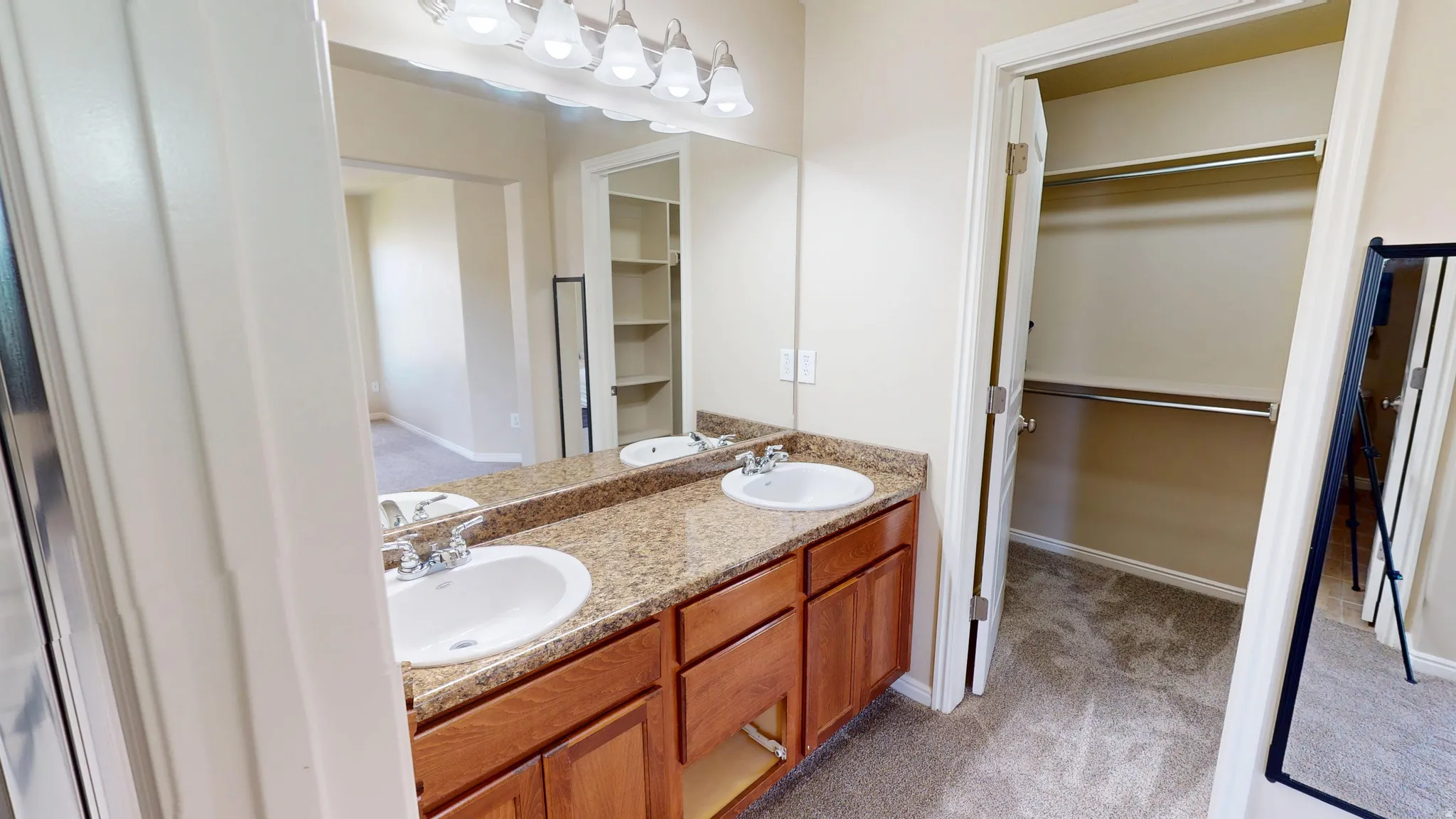 Double vanity with a speckled countertop, integrated sinks, and wood-finish cabinetry