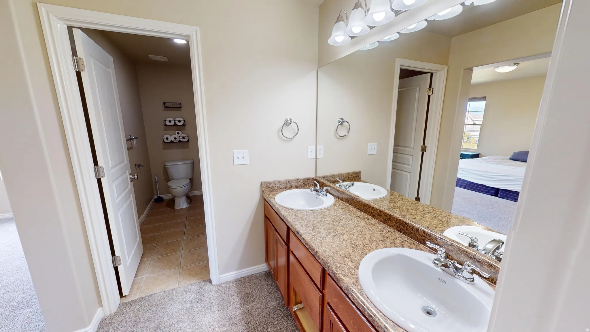 Bathroom vanity featuring dual undermount sinks, a speckled countertop, and wood-finish cabinetry