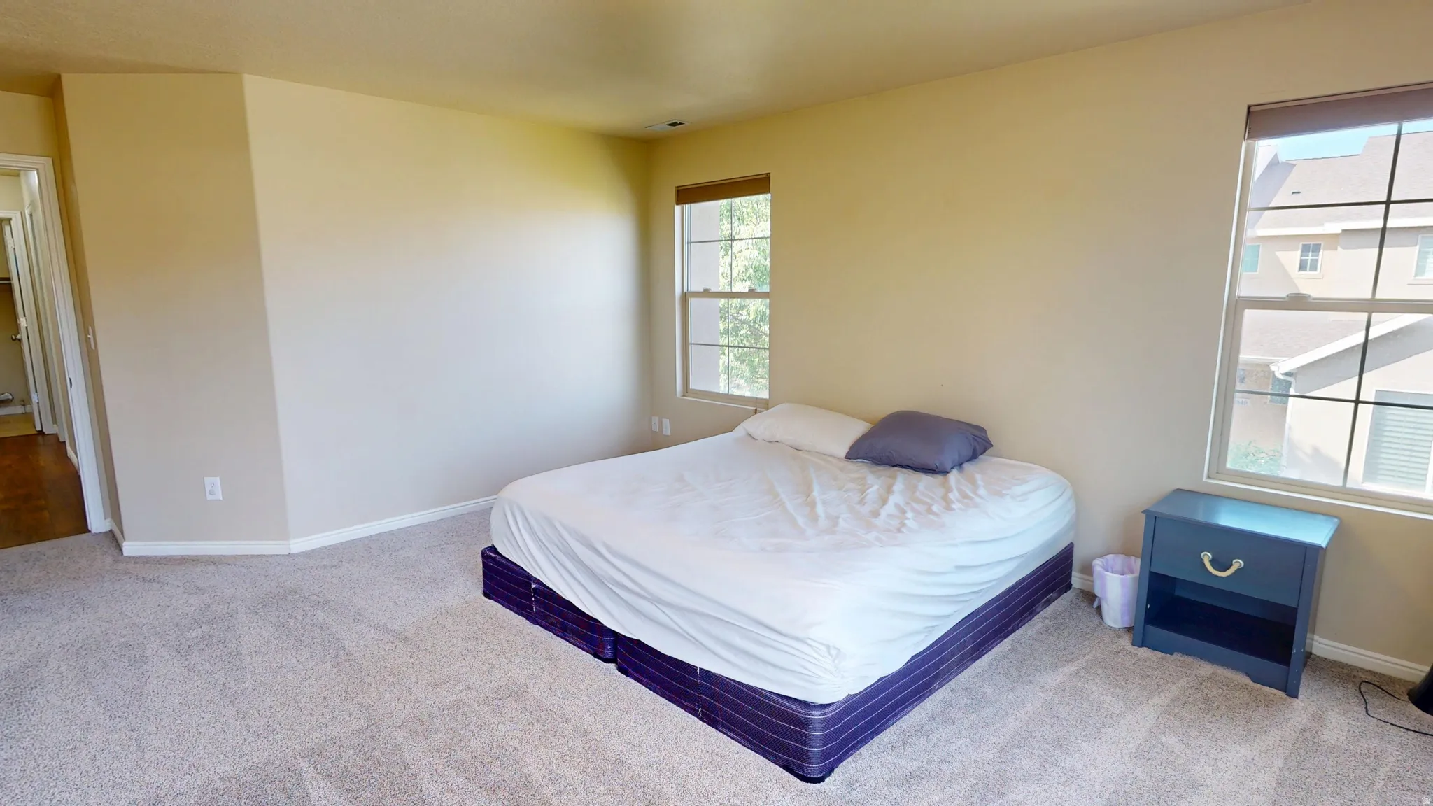 Carpeted room featuring two window openings with natural light, neutral wall tones, and recessed lighting