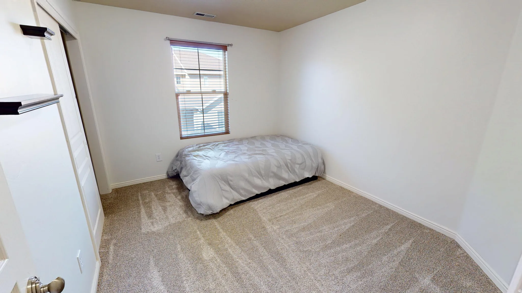 Carpeted room featuring a single window with blinds and a built-in closet with sliding doors