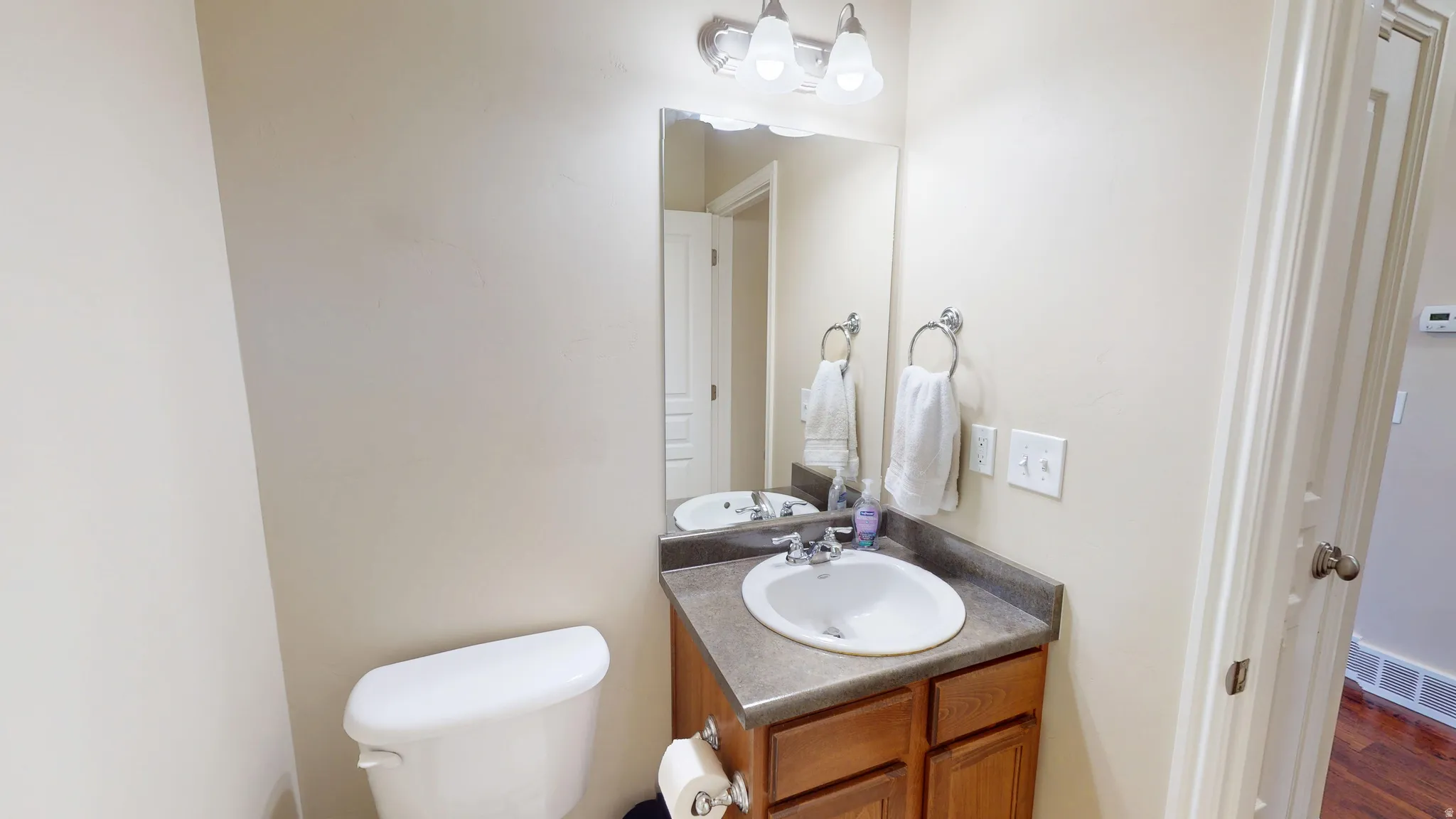 Bathroom vanity featuring a wood-finish cabinet, a countertop with an integrated sink, and an overhead vanity light