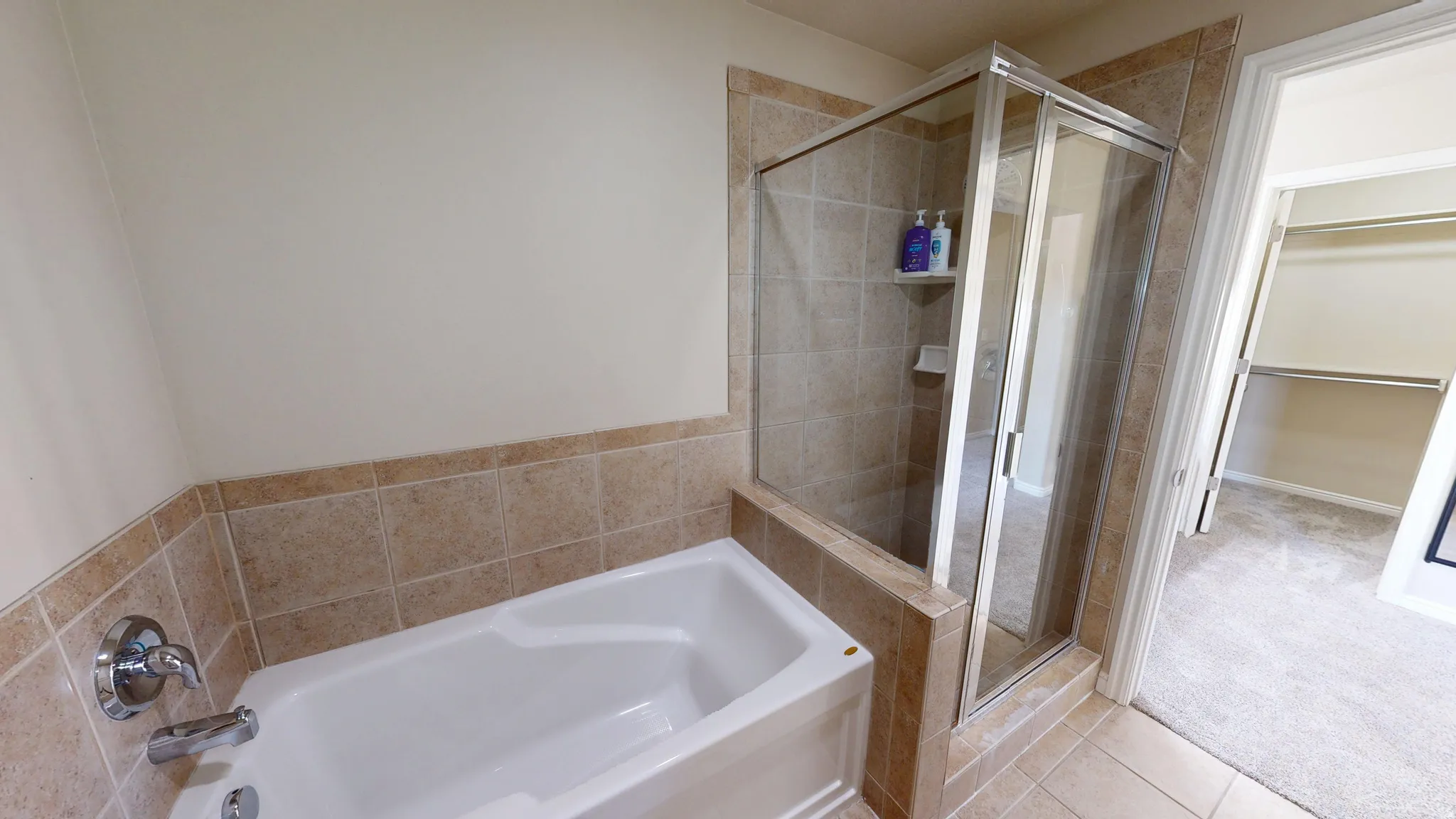 Bathtub and shower combination featuring neutral-toned tile surround and chrome fixtures