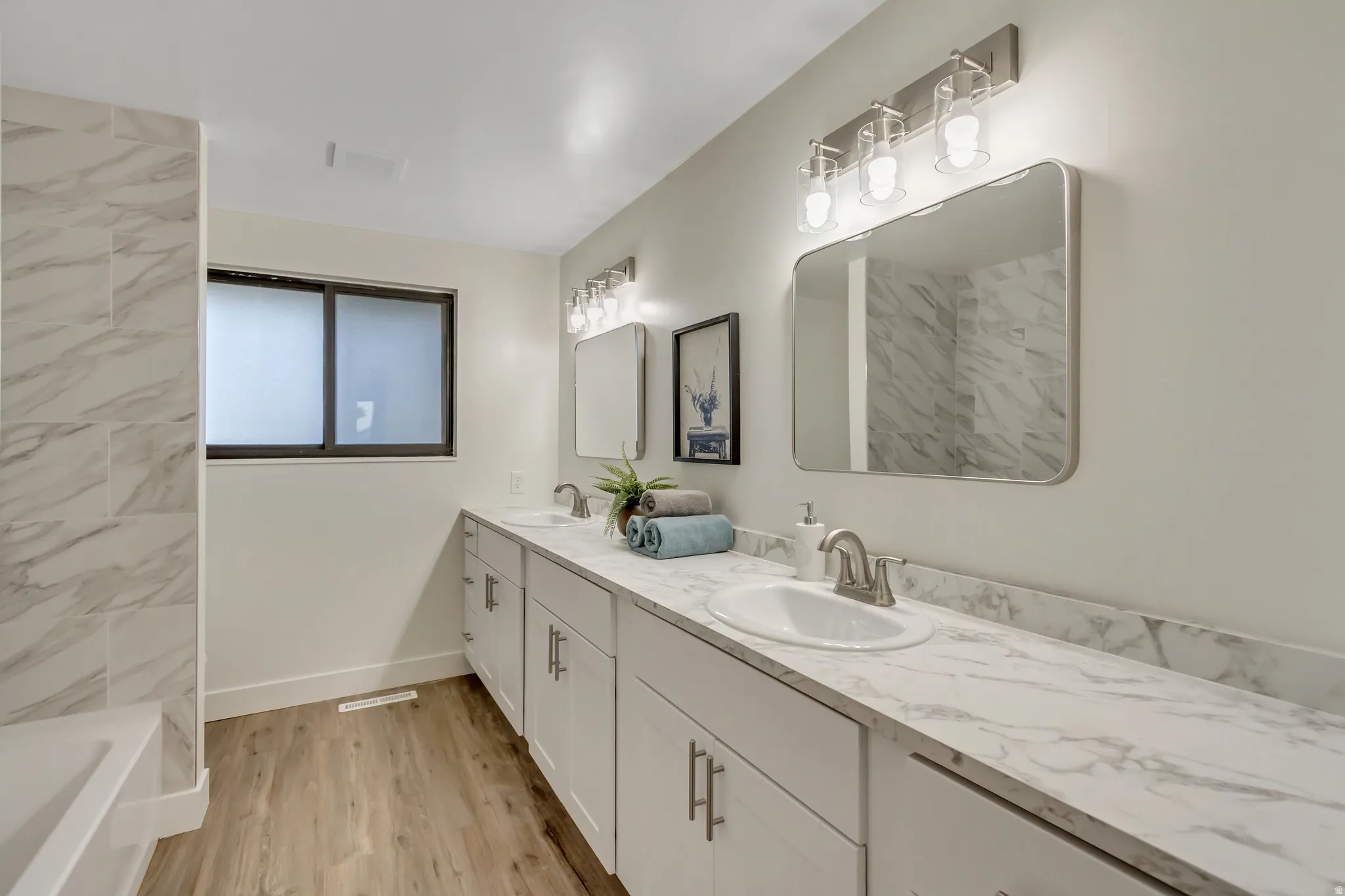 Dual vanity featuring white cabinetry, undermount sinks, and marble-finish countertops