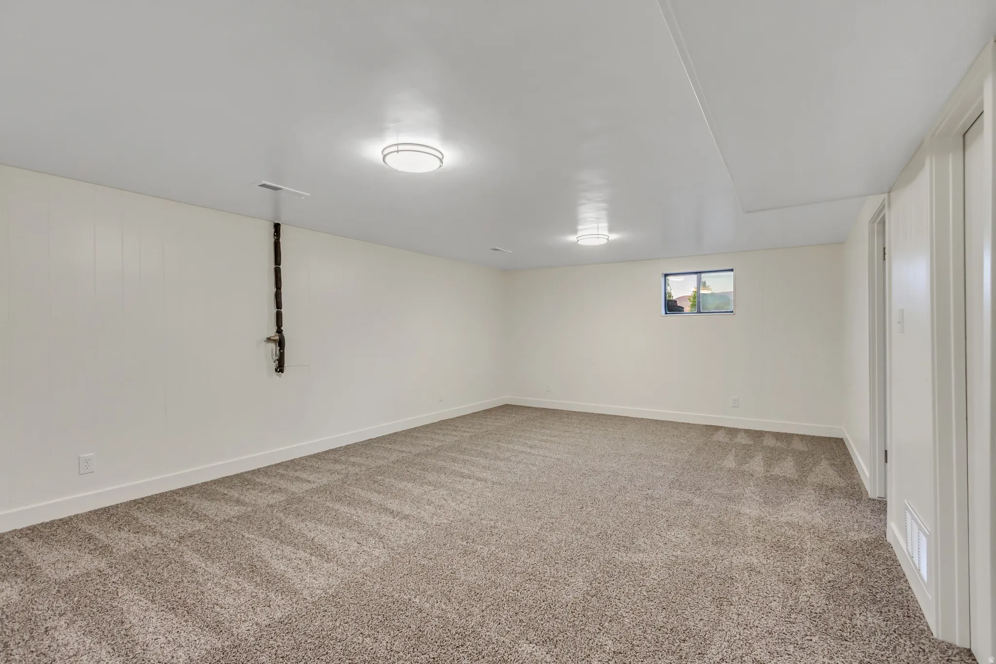Spacious room featuring neutral-toned carpeting, white walls, and recessed lighting fixtures