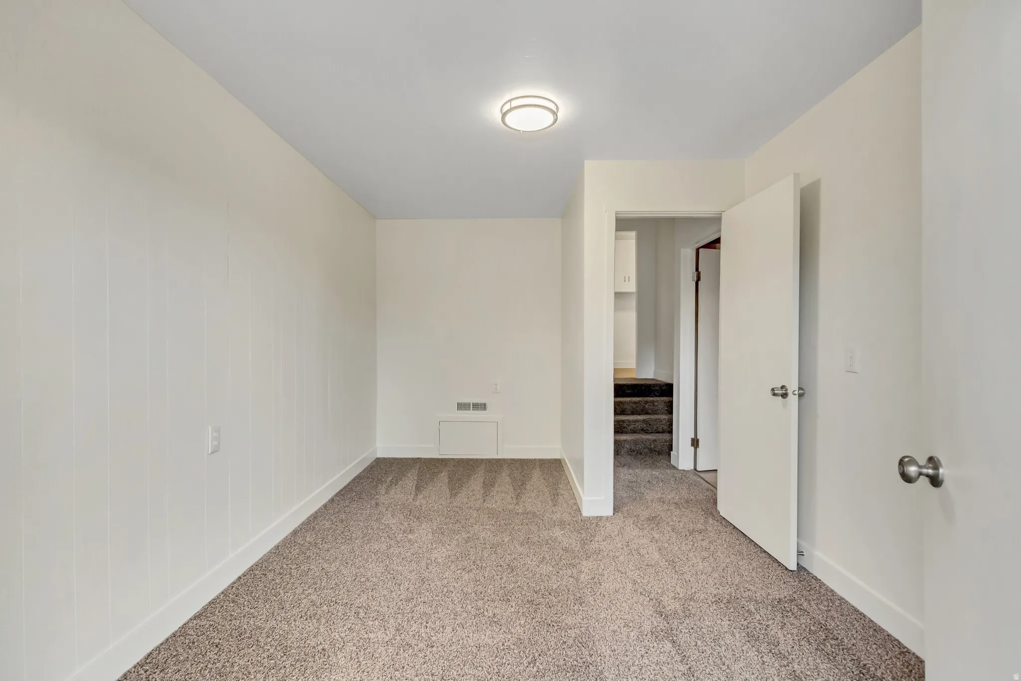 Neutral color palette room with light beige carpet flooring and white baseboards