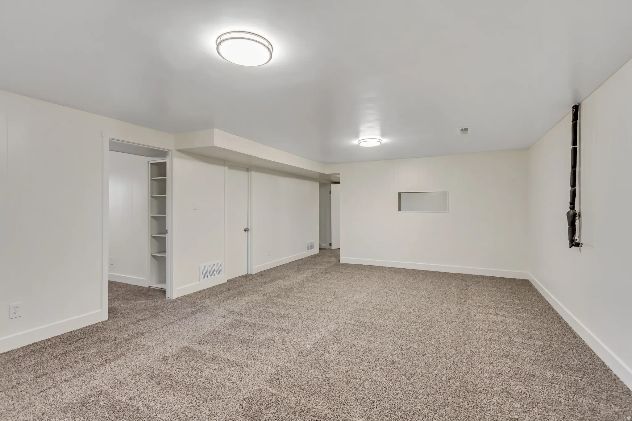 Spacious room featuring neutral carpeting, recessed lighting, and white walls
