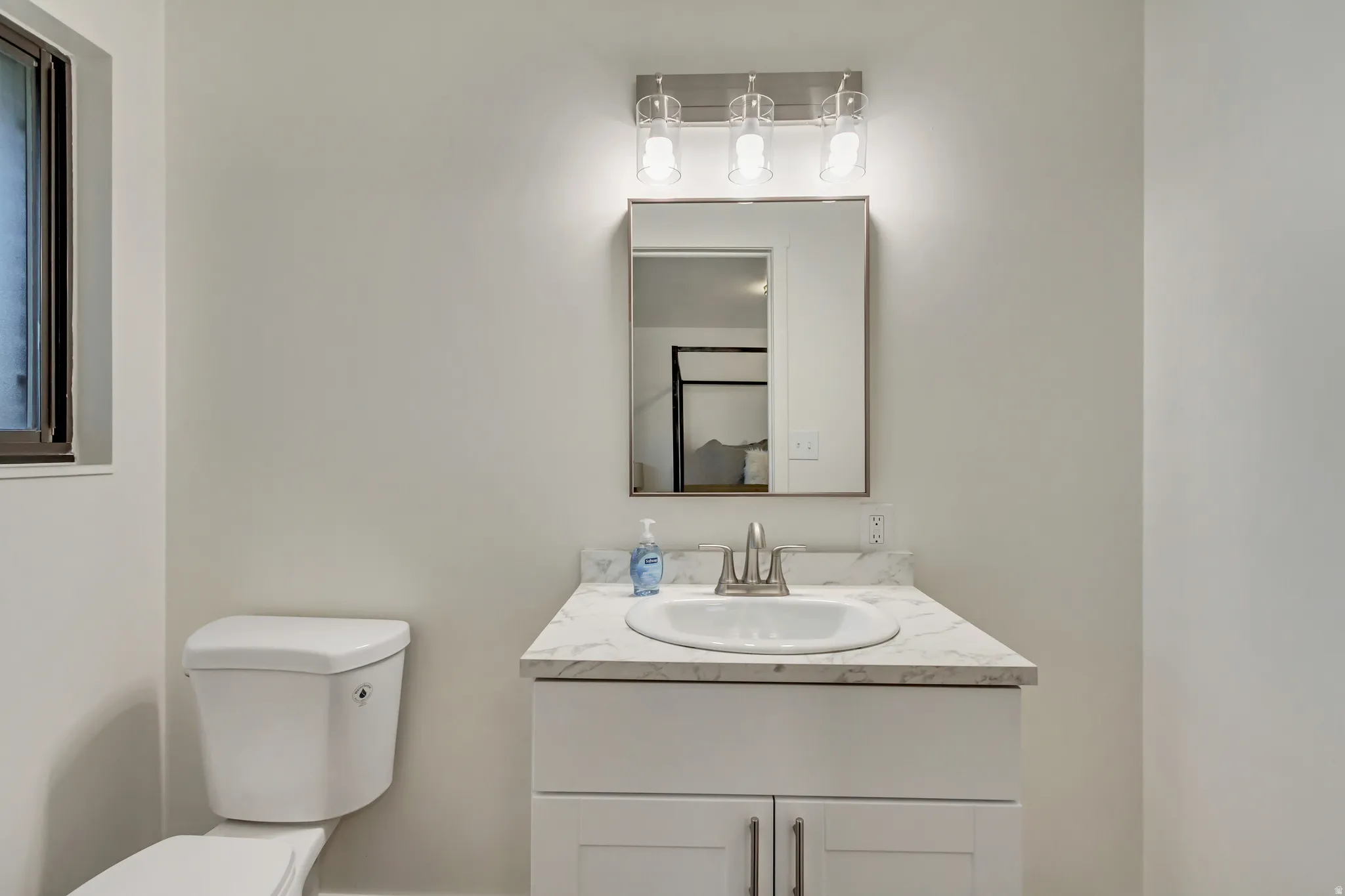Bathroom vanity featuring a white cabinet, integrated sink, and a marbled countertop