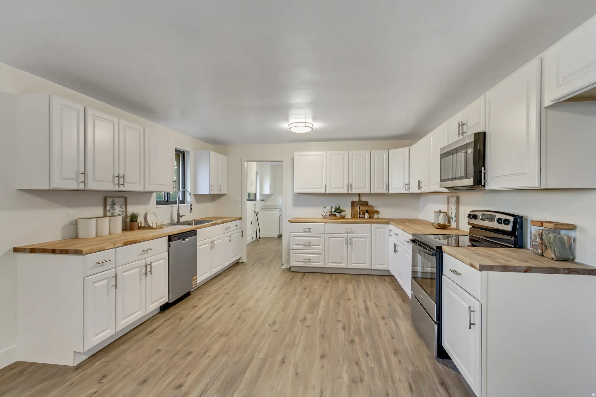 Spacious kitchen featuring extensive white cabinetry, wood-finish countertops, and wood-finish flooring