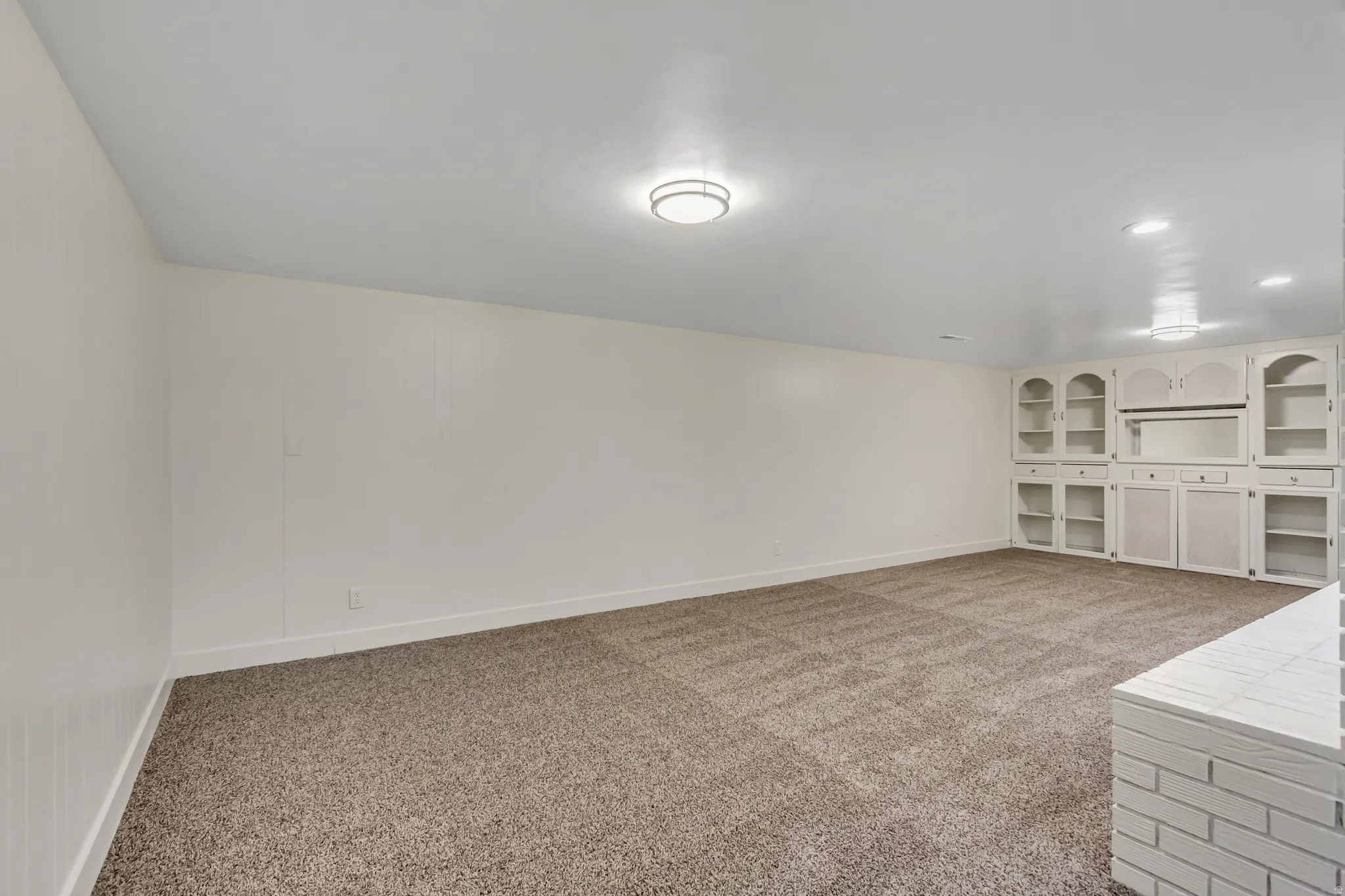 Spacious room featuring neutral carpet flooring and white walls