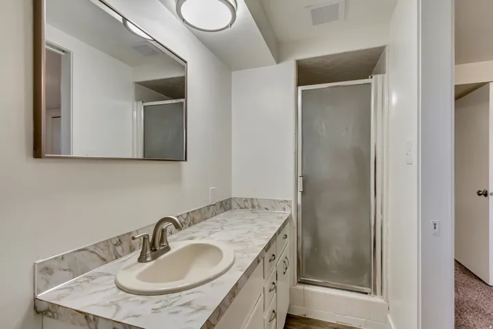 Bathroom featuring a single vanity with a laminate countertop, undermount sink, and brushed nickel faucet