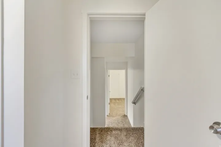 Entryway leading to carpeted stairs with a metal handrail