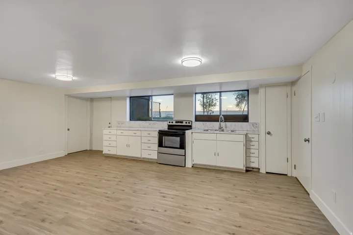 Kitchenette featuring white cabinetry, a stainless steel range, and a stainless steel sink with a window above
