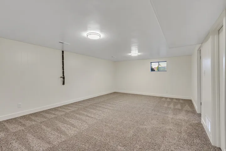 Spacious room featuring neutral-toned carpeting, white walls, and recessed lighting fixtures