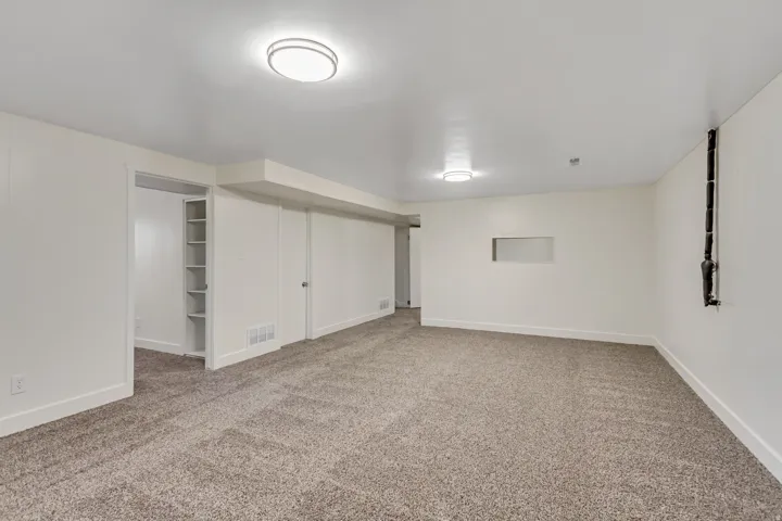Spacious room featuring neutral carpeting, recessed lighting, and white walls