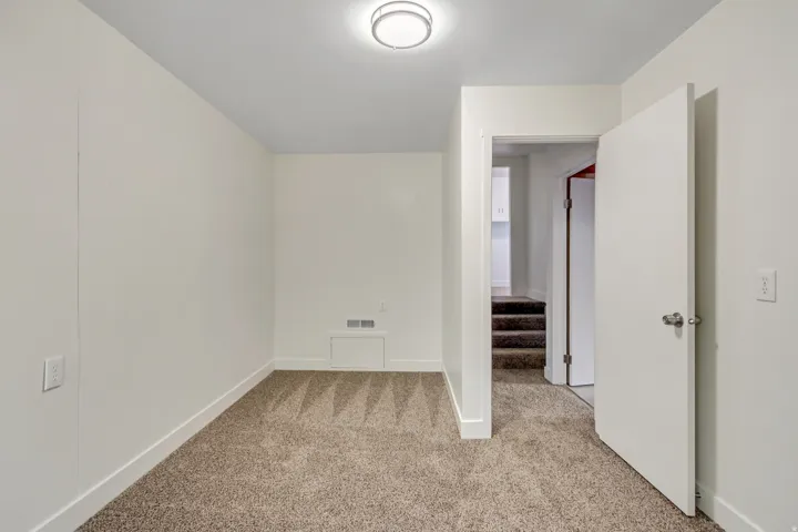 Carpeted room with white walls and a ceiling-mounted light fixture