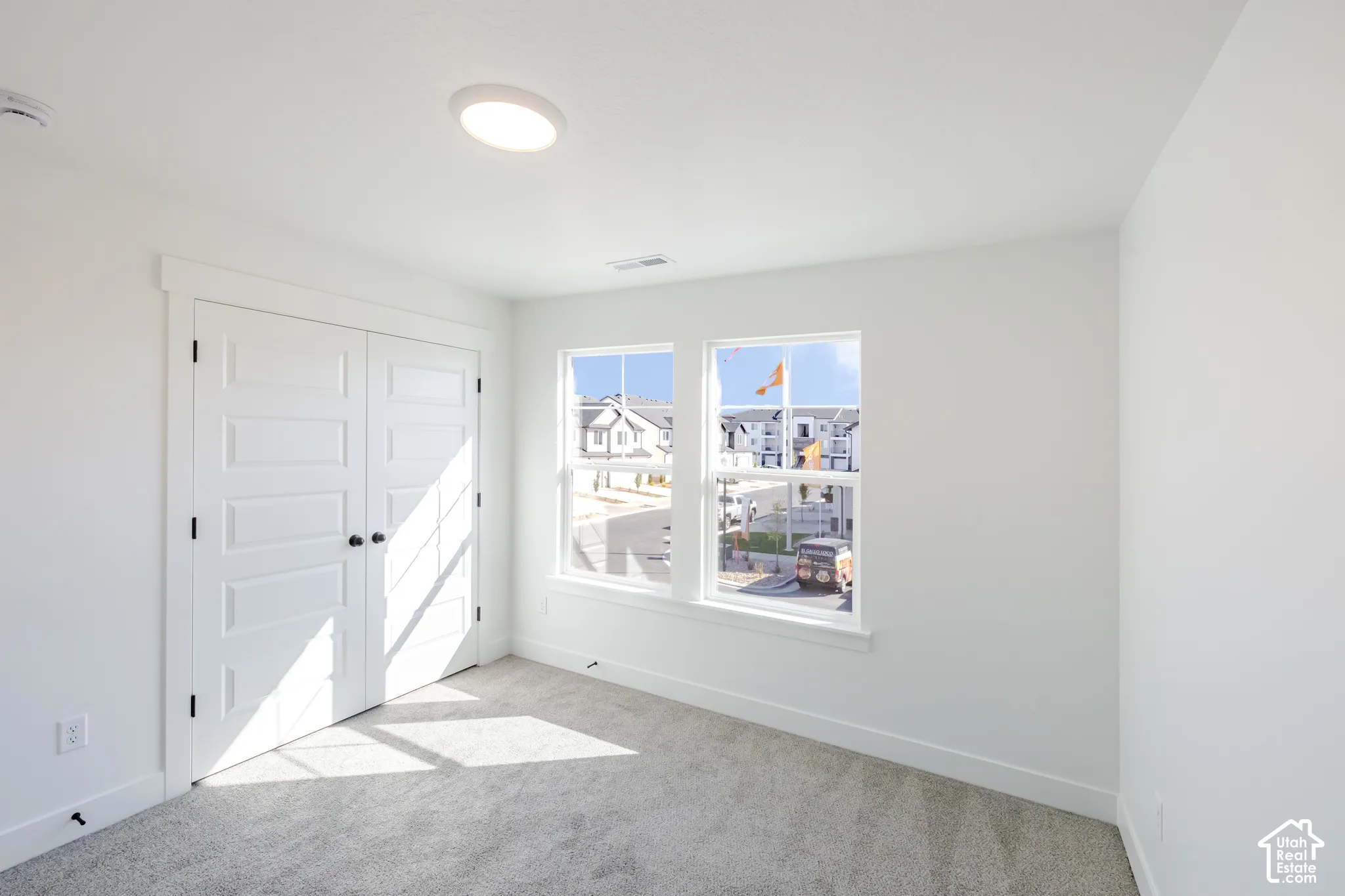 Neutral-toned carpeted flooring, dual-panel closet doors, and dual windows with white trim