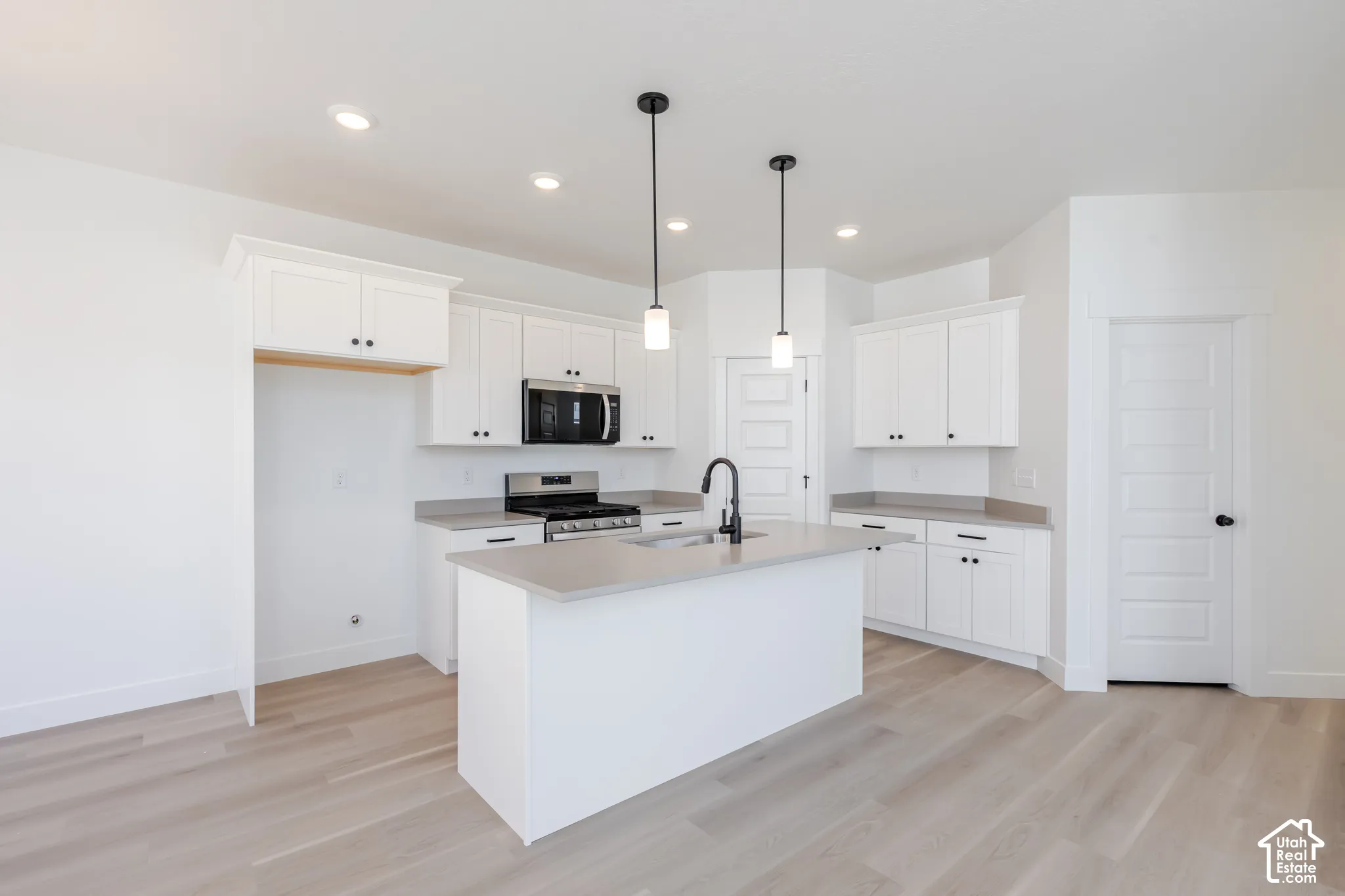 Kitchen featuring white cabinetry, quartz countertops, wood-finish flooring, dual pendant lighting, and a matte black gooseneck faucet