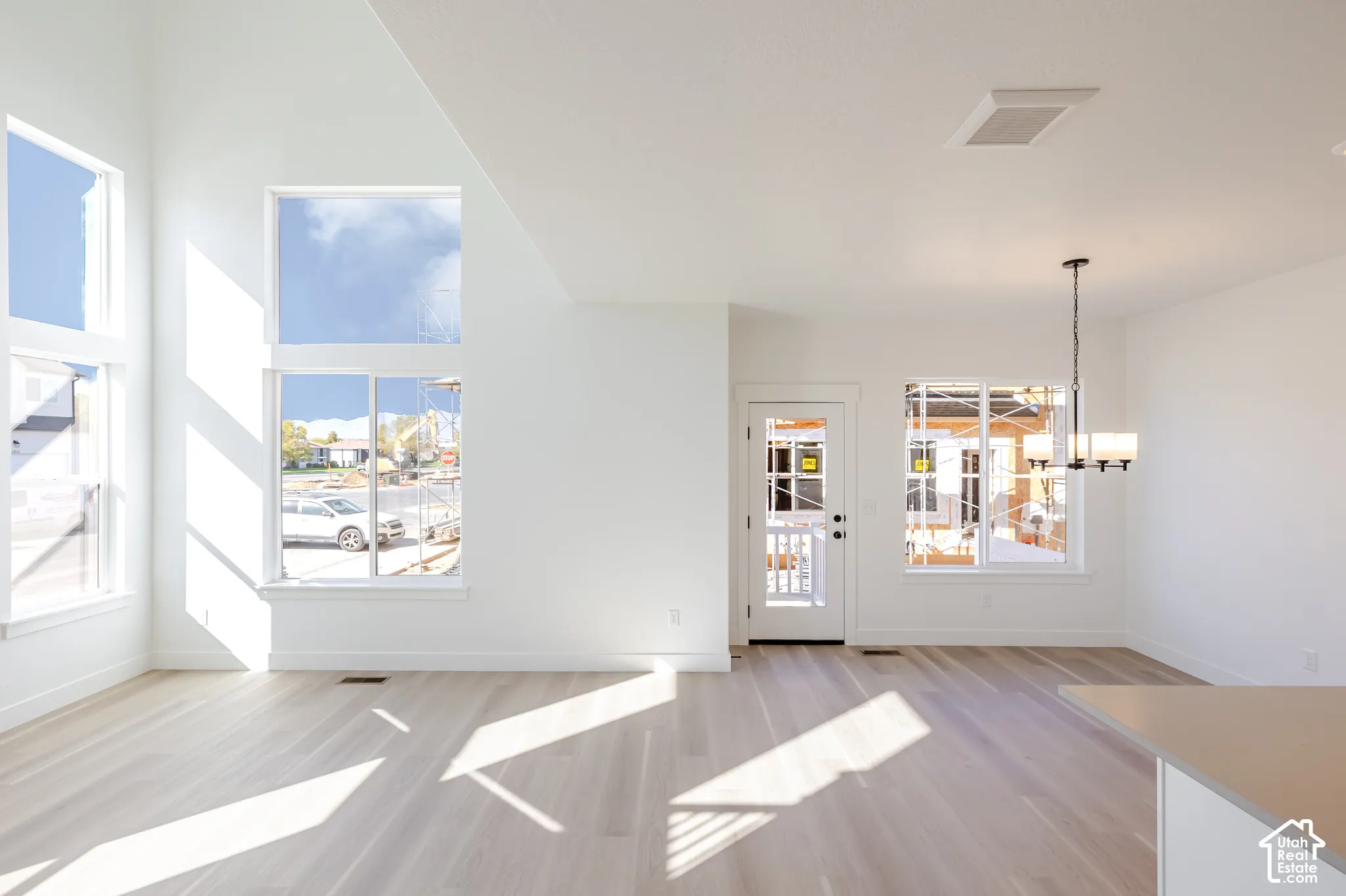 Vaulted ceilings, expansive windows, wood-finish flooring, and a multi-arm pendant light fixture