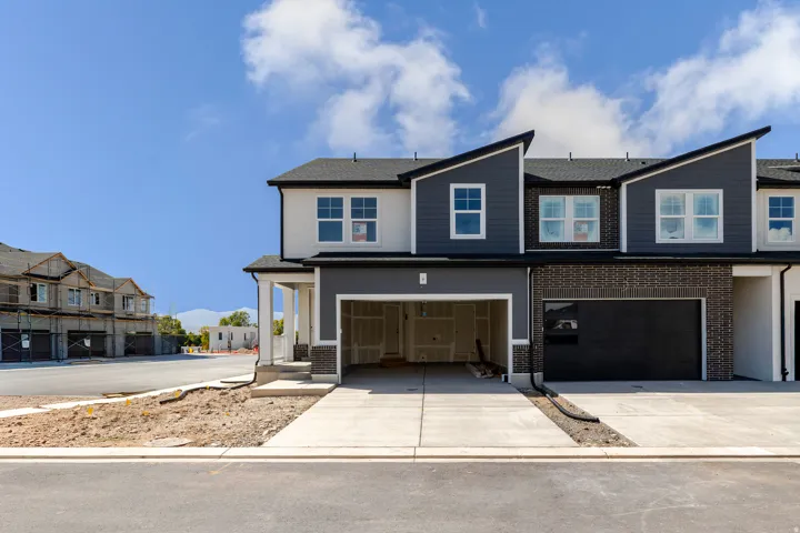 Contemporary facade featuring mixed materials, a covered porch, an attached garage, and a concrete driveway