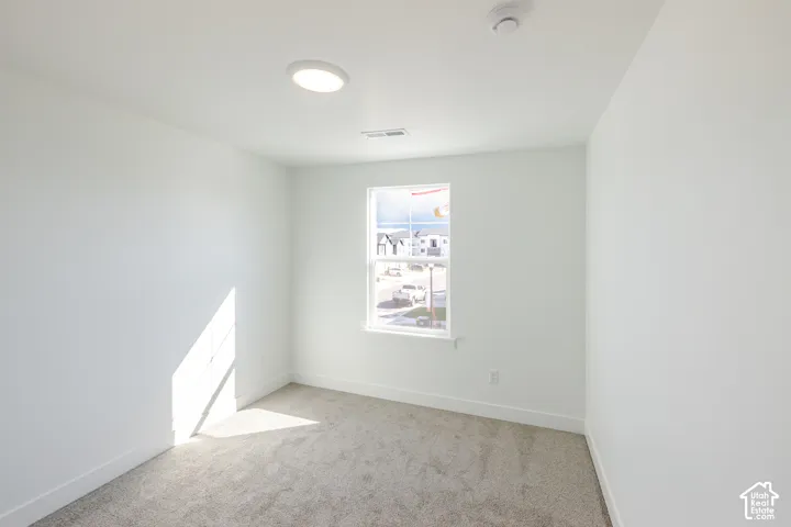 Neutral-toned wall paint, plush carpeting, a single-hung window, and a modern flush-mount LED ceiling light fixture