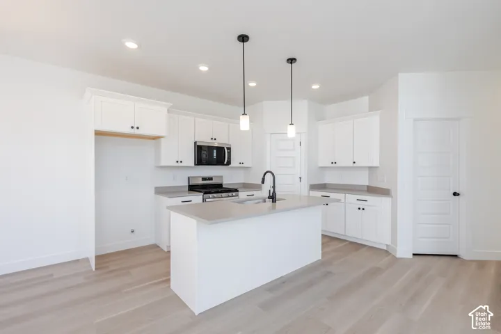 Kitchen featuring white cabinetry, quartz countertops, wood-finish flooring, dual pendant lighting, and a matte black gooseneck faucet