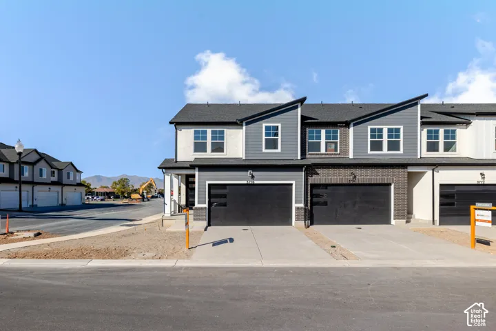 Contemporary multi-level exterior featuring a combination of horizontal lap siding and brick masonry, shed-style rooflines, and double-car garages with paneled doors