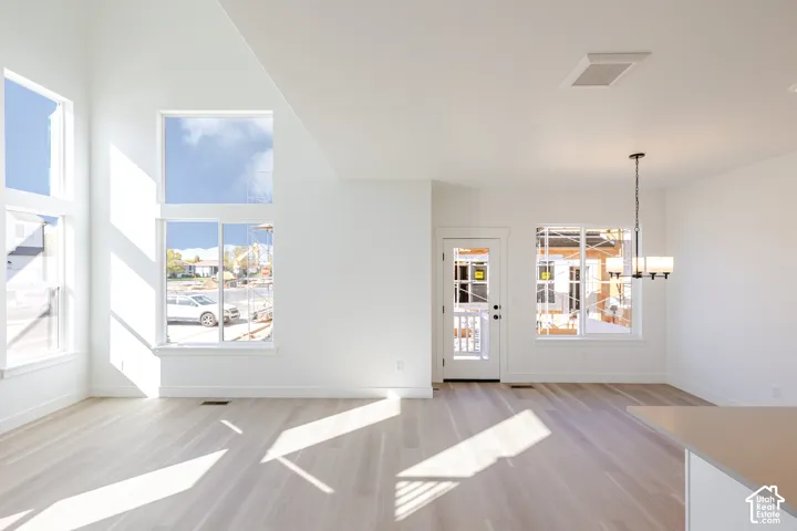Vaulted ceilings, expansive windows, wood-finish flooring, and a multi-arm pendant light fixture