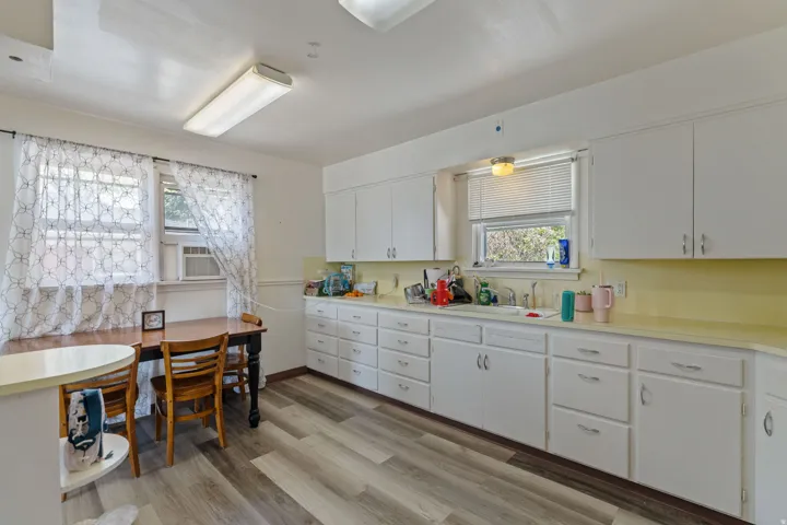 Kitchen featuring extensive white cabinetry, light-toned countertops, and wood-finish flooring