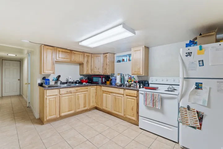 Kitchen featuring light wood-finish cabinetry, a double basin sink, and ample countertop space