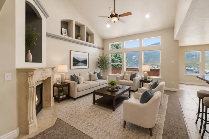Vaulted ceilings enhance this living space featuring a detailed fireplace surround, integrated architectural shelving, and a prominent window wall with mountain scenery