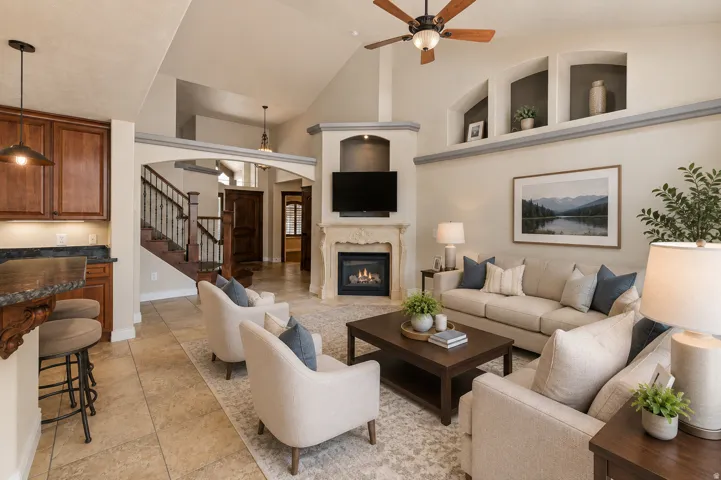 Living area featuring a vaulted ceiling with a ceiling fan, a fireplace with an ornate mantel, a built-in entertainment niche, and decorative wall cutouts