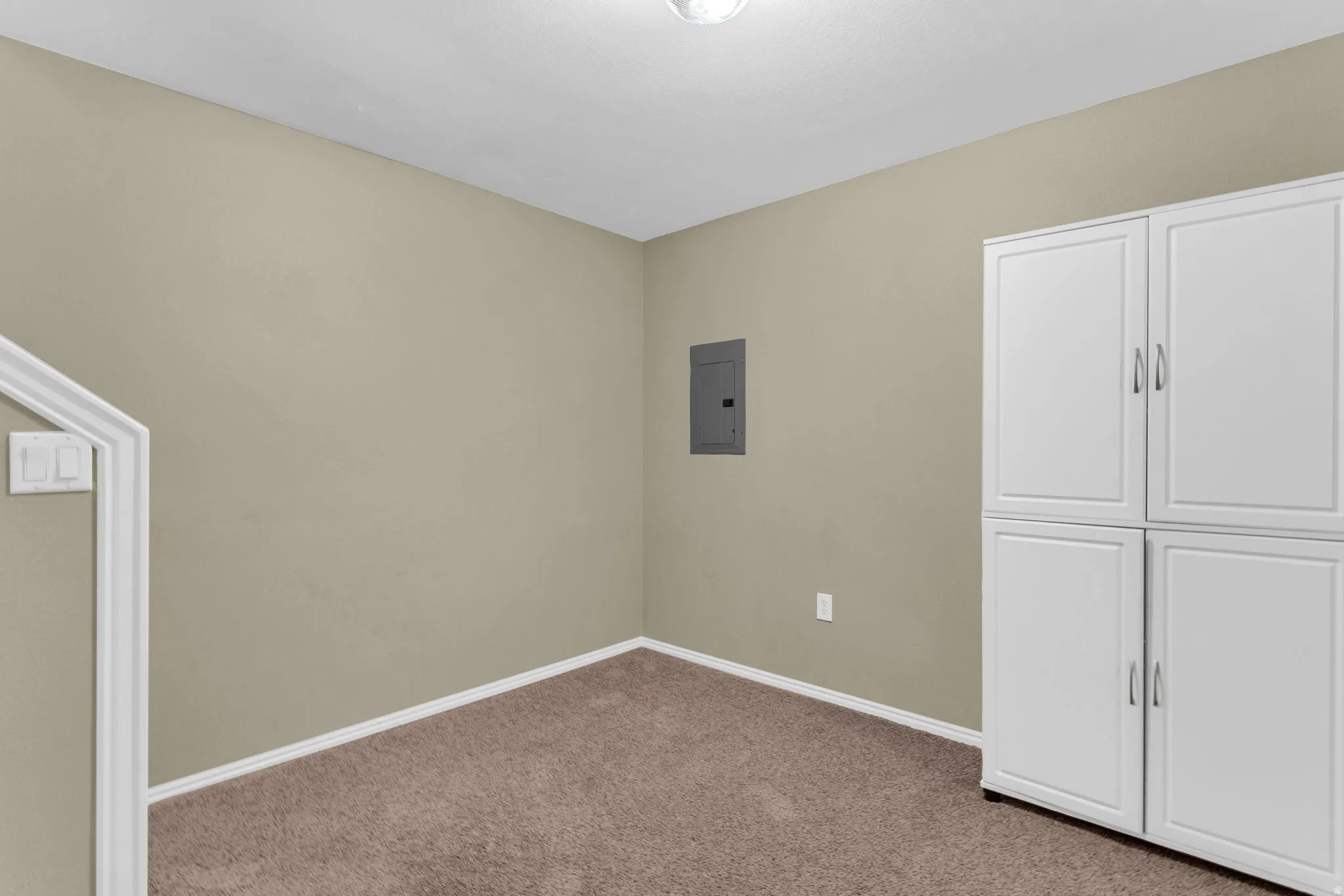Integrated white storage cabinetry with brushed nickel hardware, neutral-toned walls, and brown carpeting
