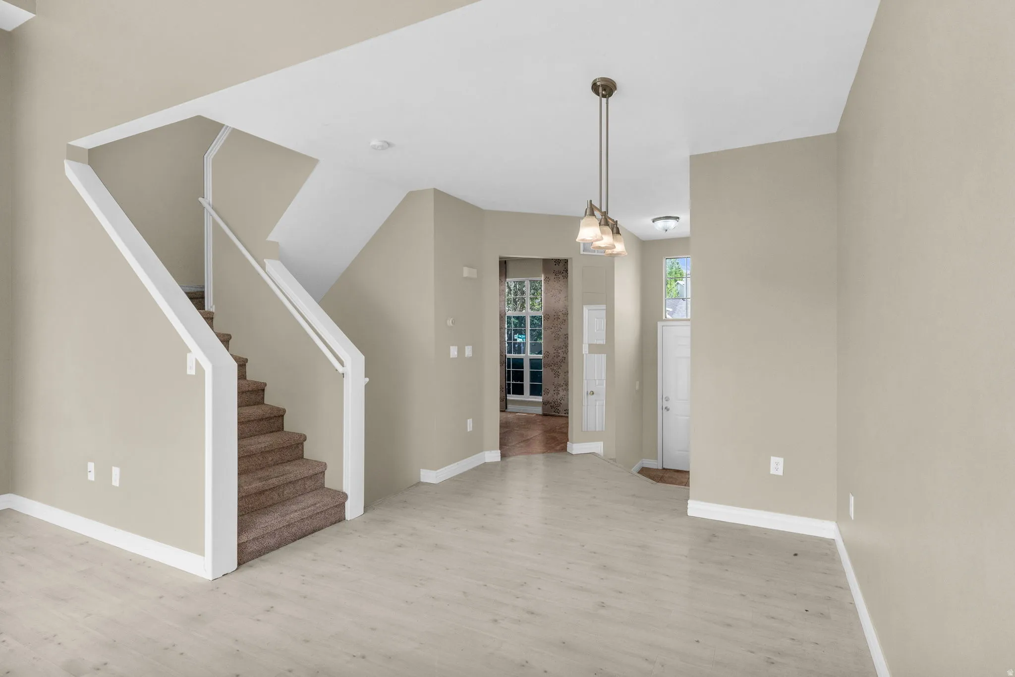 Spacious main living area featuring light wood-finish flooring and a neutral wall palette