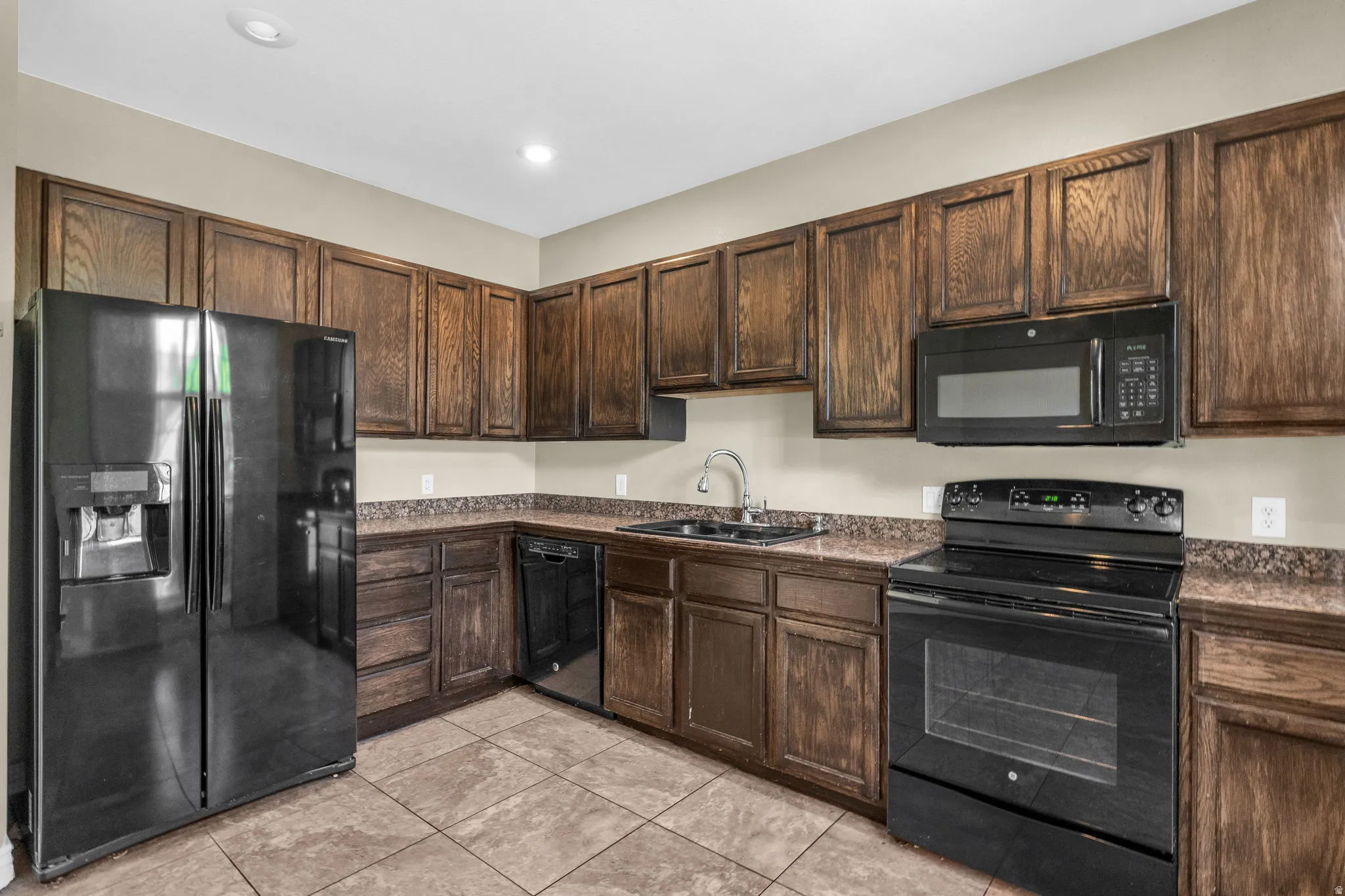 Kitchen featuring extensive wood cabinetry, coordinating countertops, and tile flooring