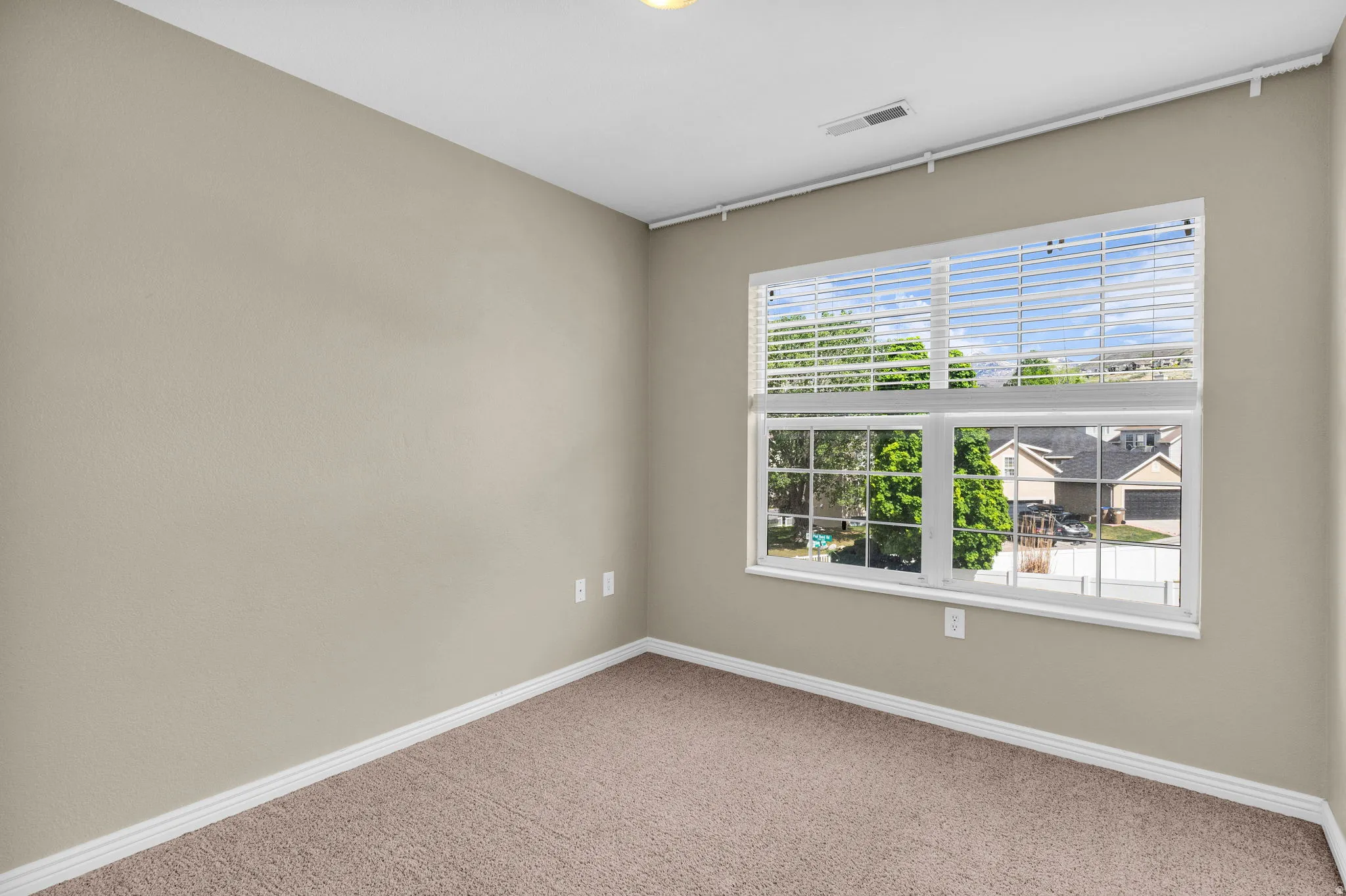 Neutral tone wall paint with white baseboards and textured carpeting