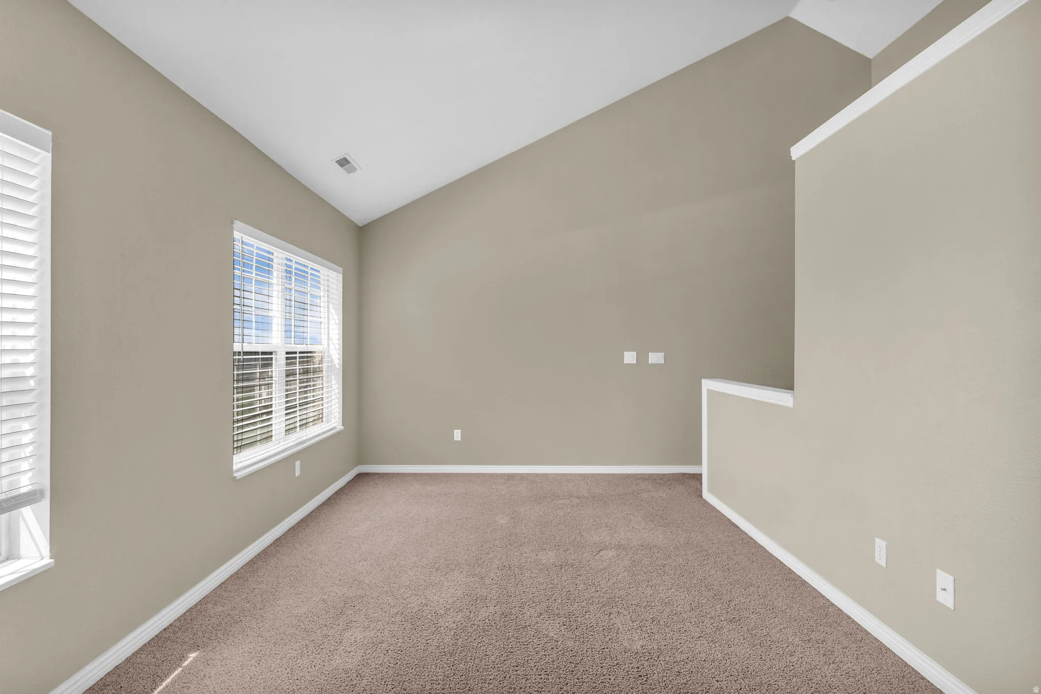 Room featuring vaulted ceilings and neutral wall tones