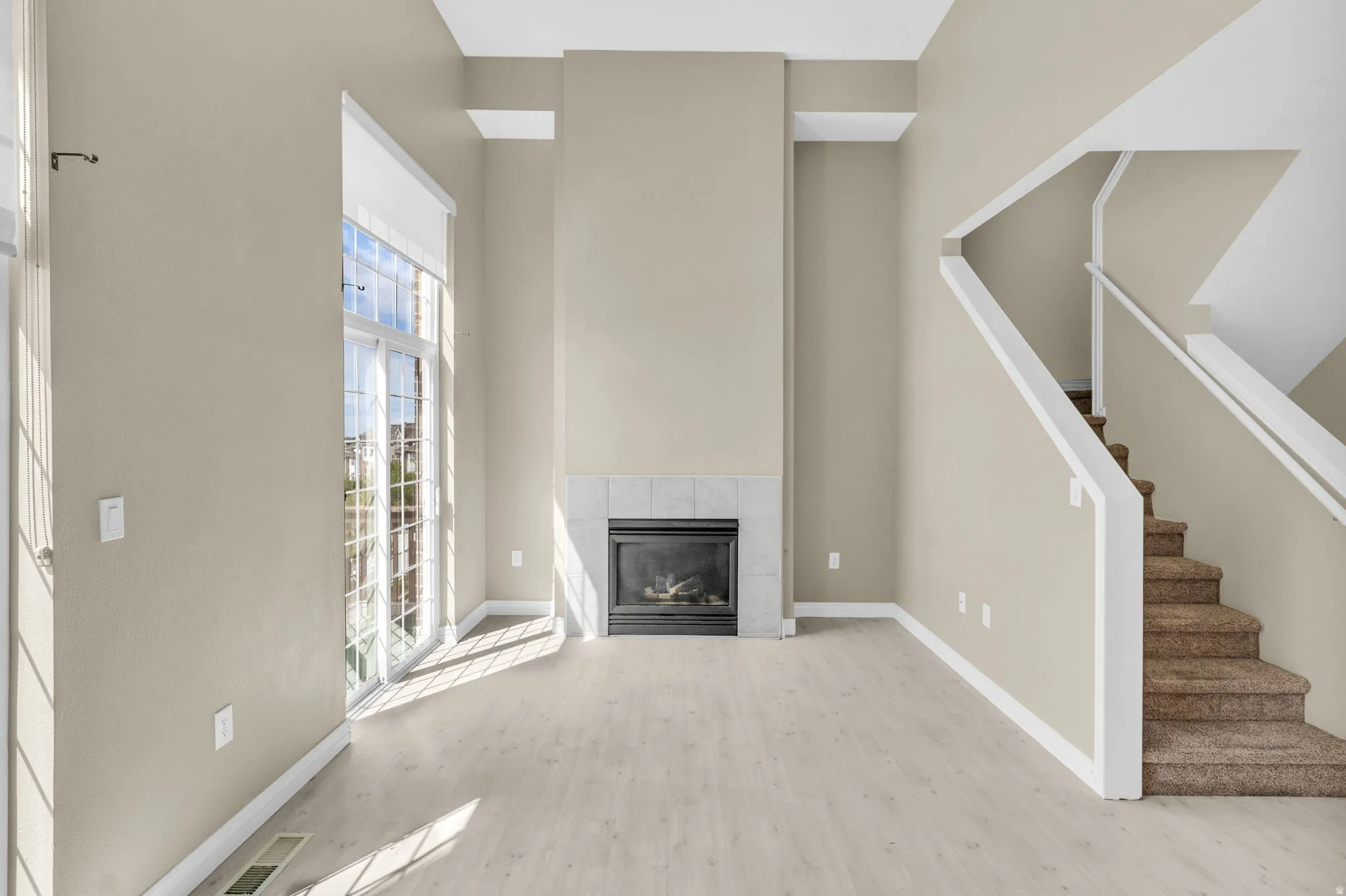 Spacious living area featuring a fireplace with a tile surround, large glass sliding doors, and wood-finish flooring